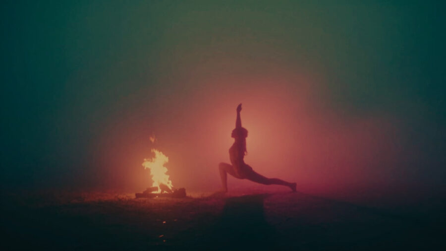 dynamische Schattenfigur in Asana am Feuer zur Sommersonnwende