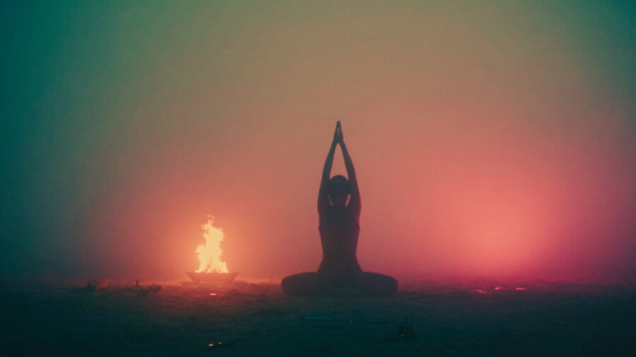 Schattenfigur in Asana am Feuer zur Sommersonnwende.